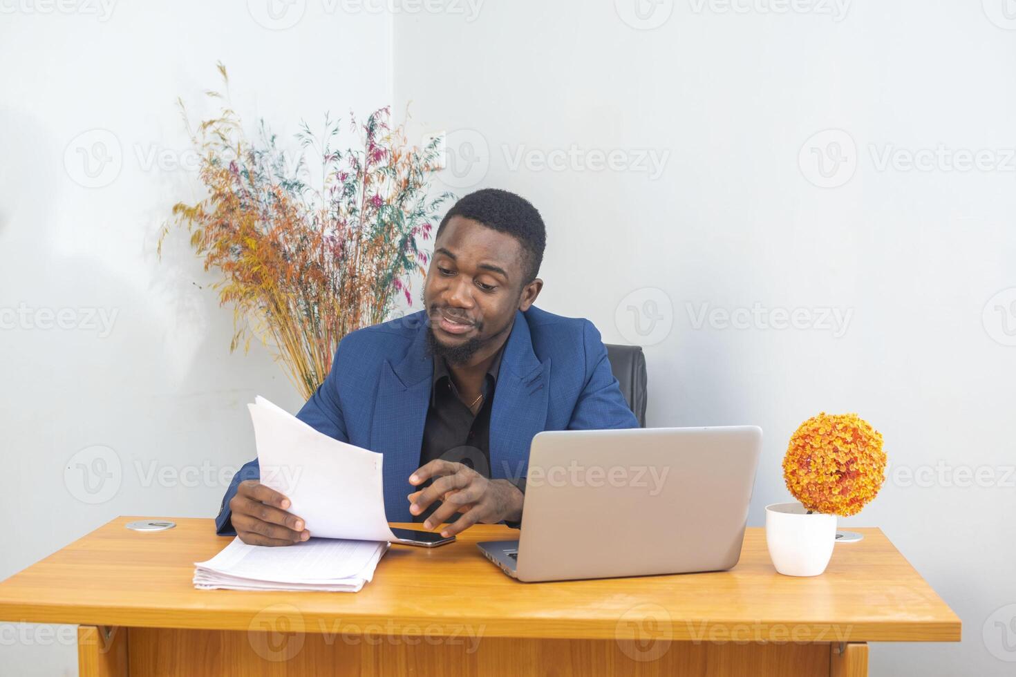 Ethnic young man reading document and writing in planner while sitting at table and working on remote project at home photo