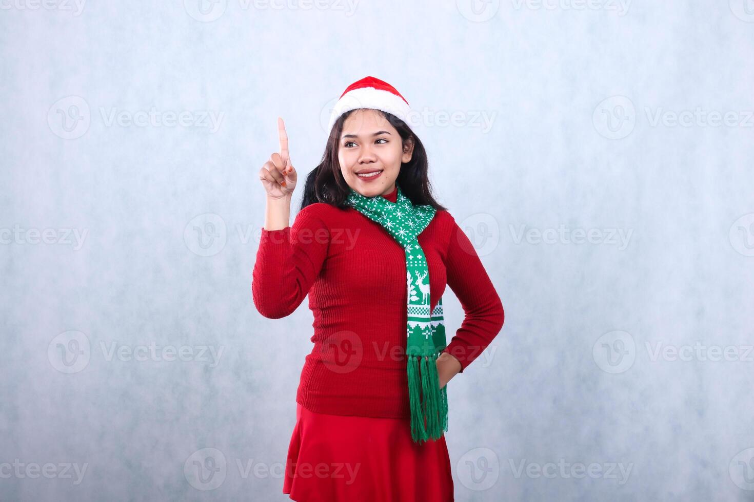 Asian woman gesture wearing red sweater party wear with Santa hat and scarf, left slant hold waist and touch and look right, celebrating christmas and new year isolated on white background photo