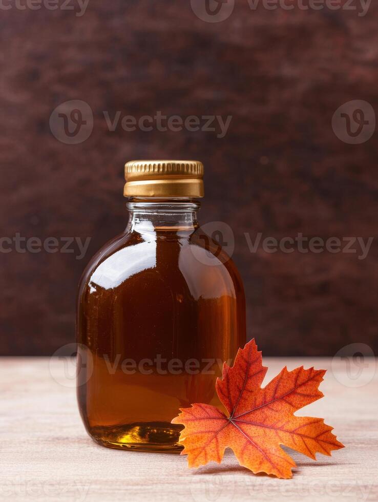 Maple syrup bottle with autumn leaf photo