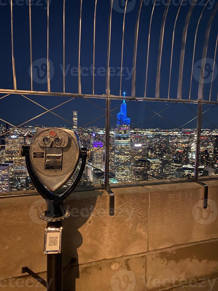 A coin operated binoculars on top of a building overlooking the city photo