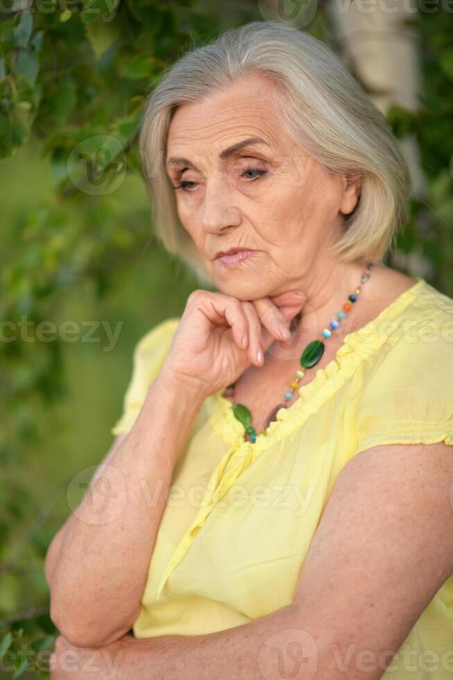 Portait of beautiful sad senior woman in park photo