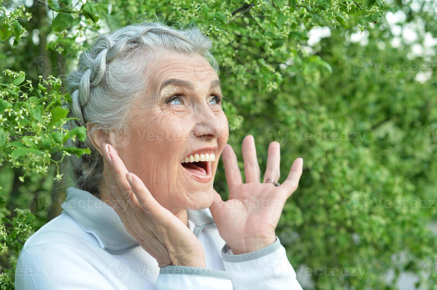 Close-up portrait of happy senior beautiful woman posing in park photo