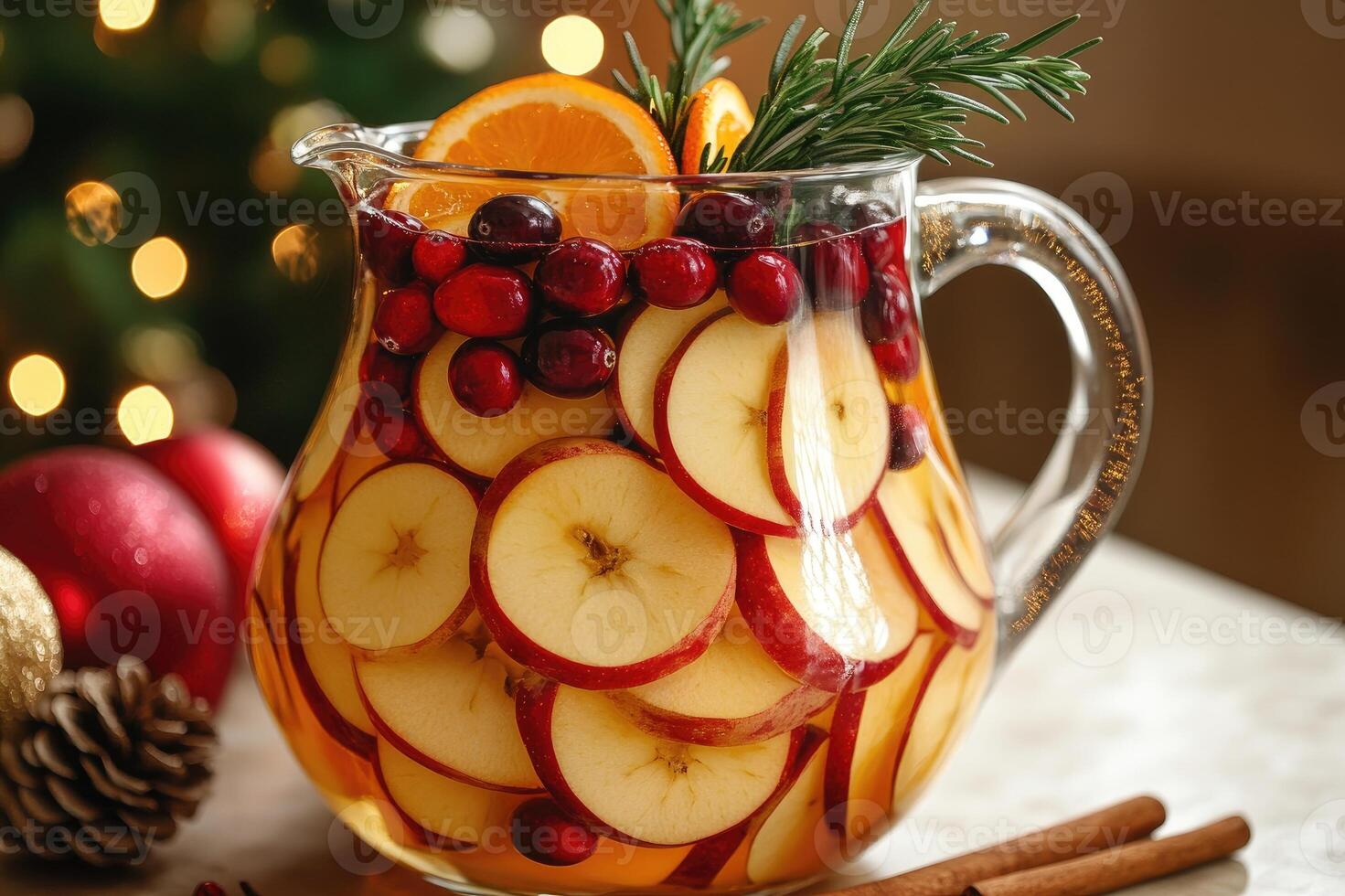 Christmas sangria with apple, orange, cranberry and cinnamon sticks in a glass pitcher photo