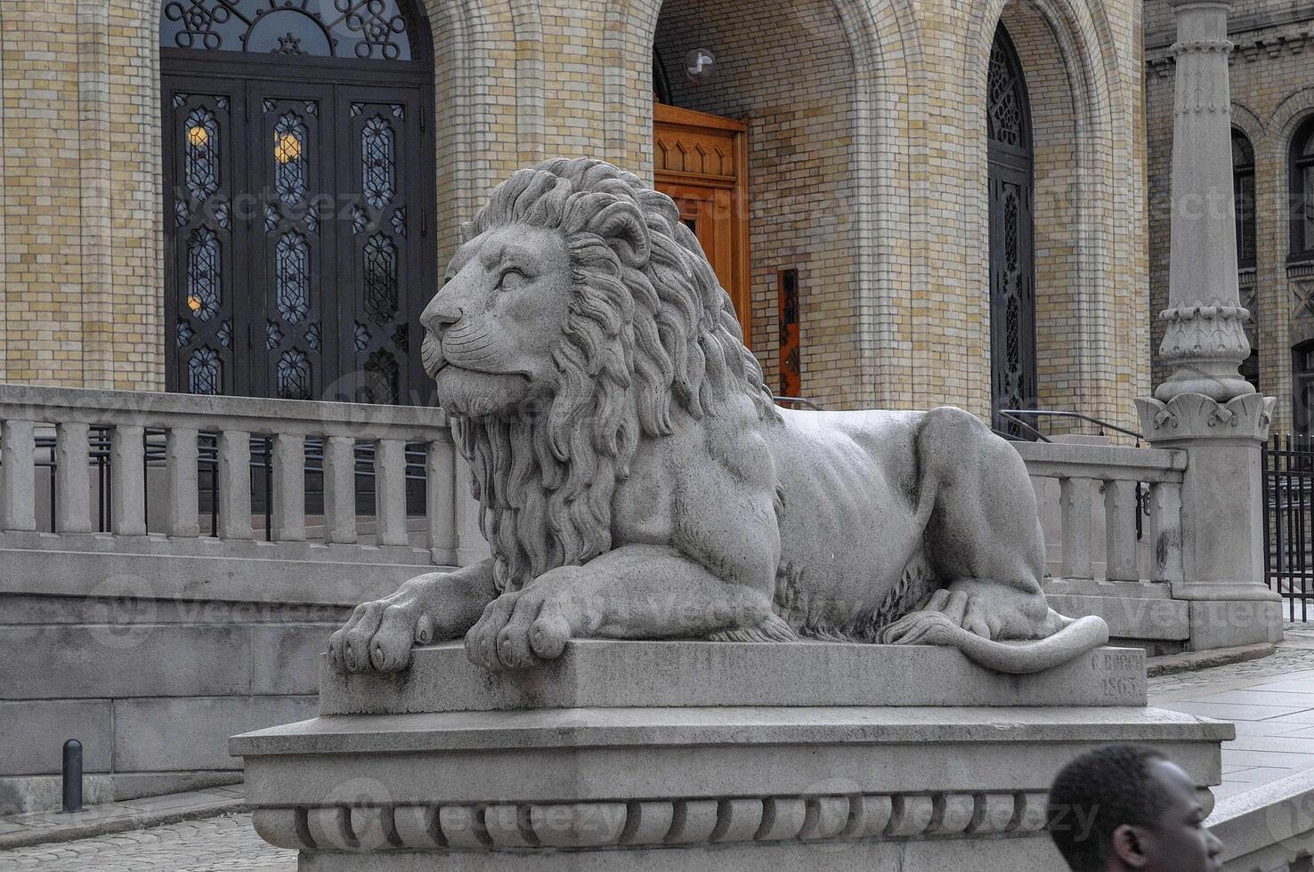 A statue of a lion sitting on a stone ledge in oslo photo