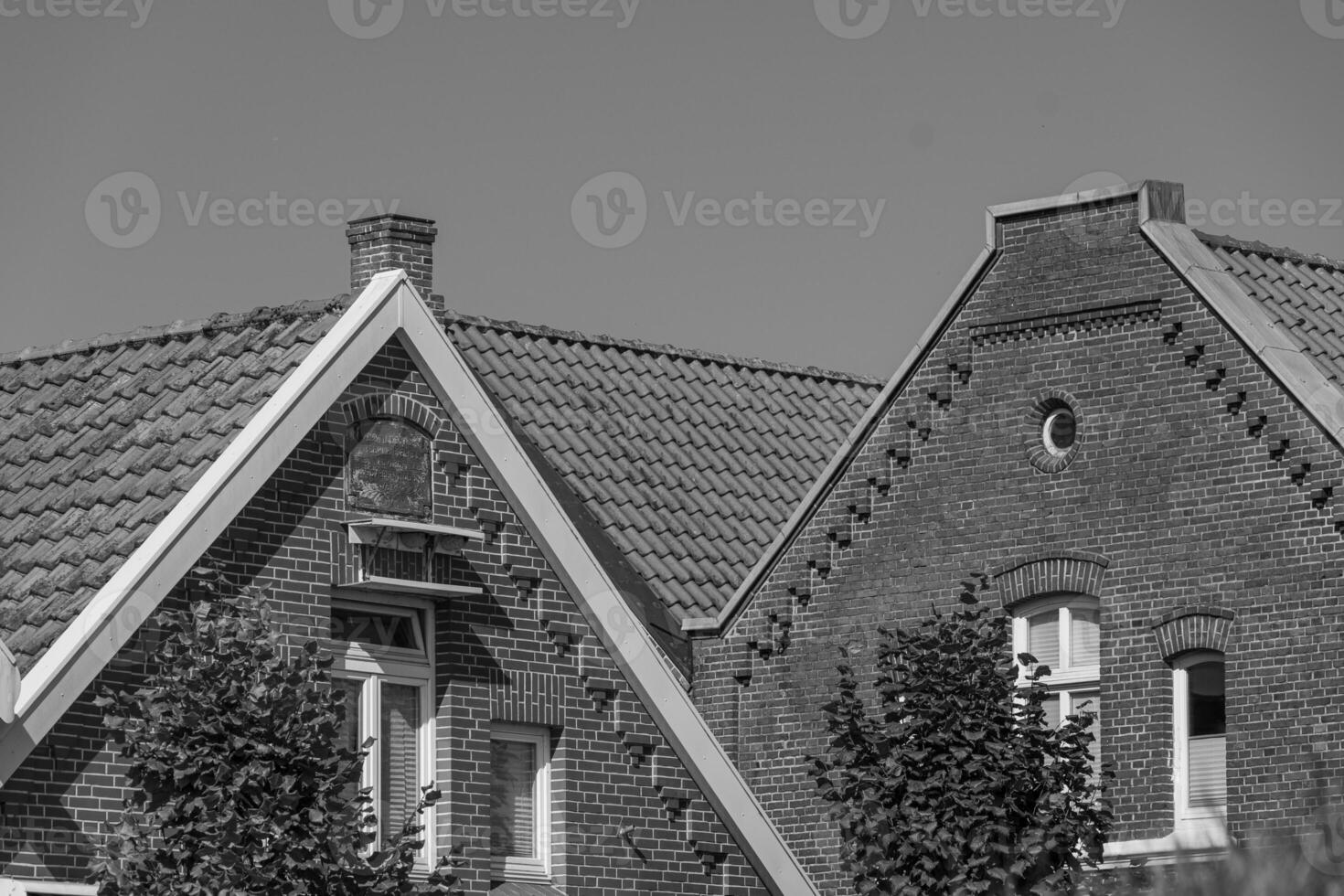 A black and white photo of a house with a clock on it