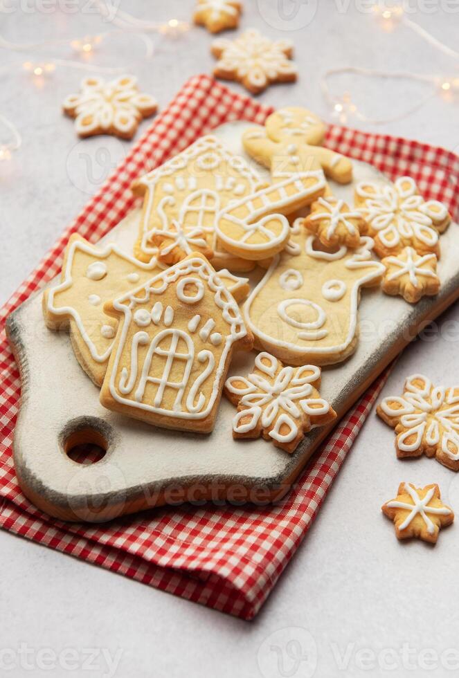 Christmas cookies decorated with icing lying on white cutting board photo