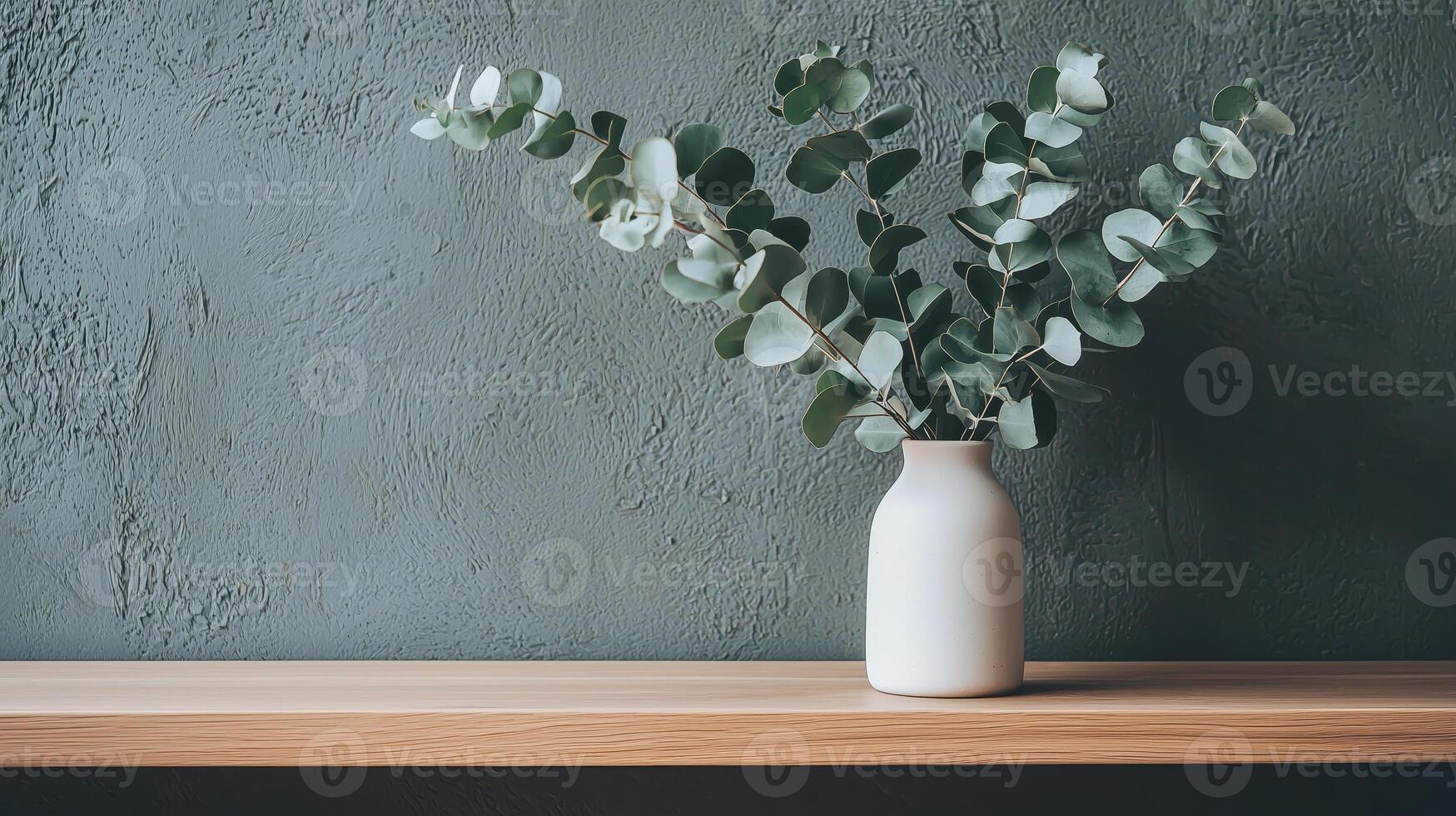 A white vase with eucalyptus leaves sitting on a shelf photo