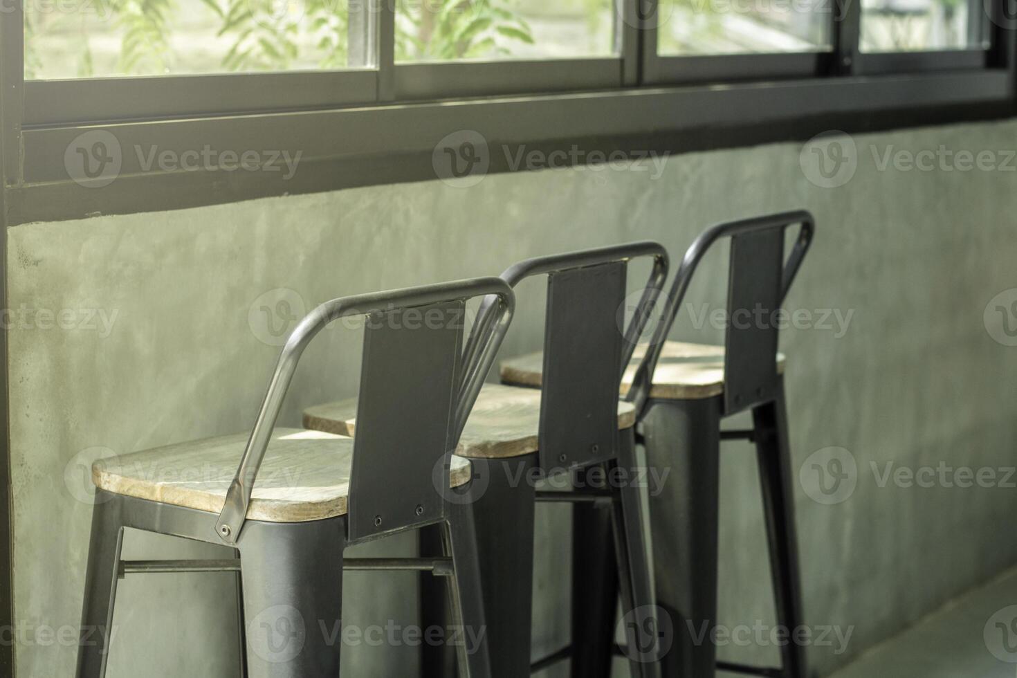 Bar stool in the loft style shop near the window glass with morning sunshine from outside. Window bar stools in cafes. photo