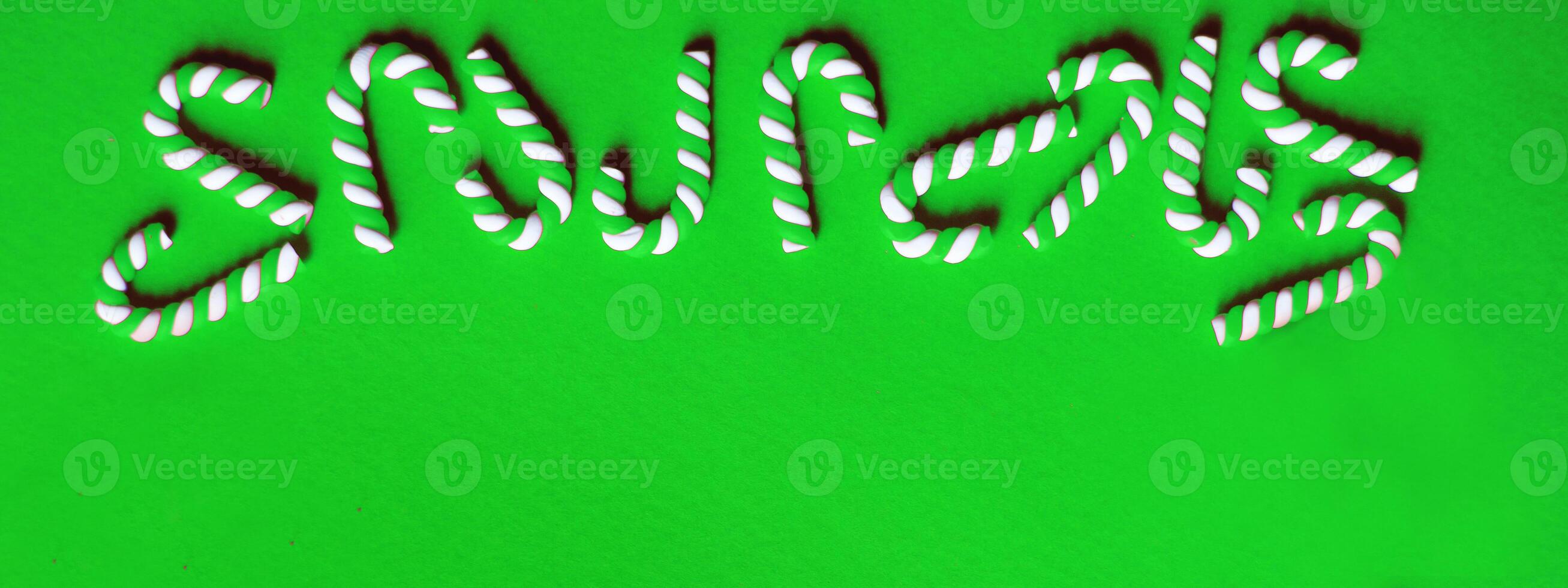 Christmas composition with frame of candy canes on a green background. photo