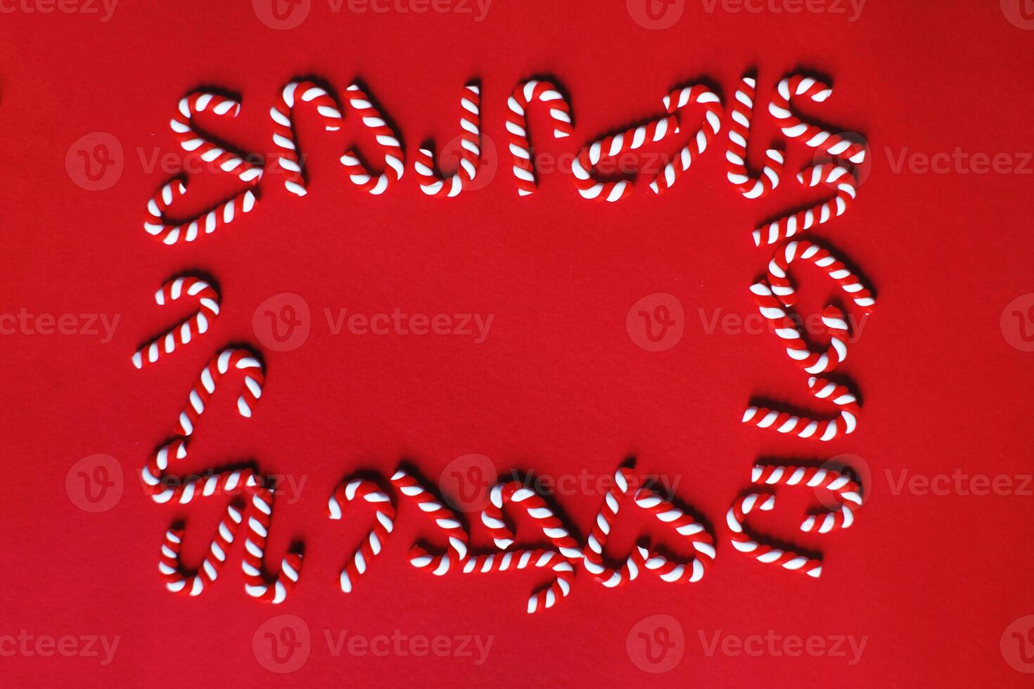Flat lay Christmas composition with frame of candy canes on a red background. photo