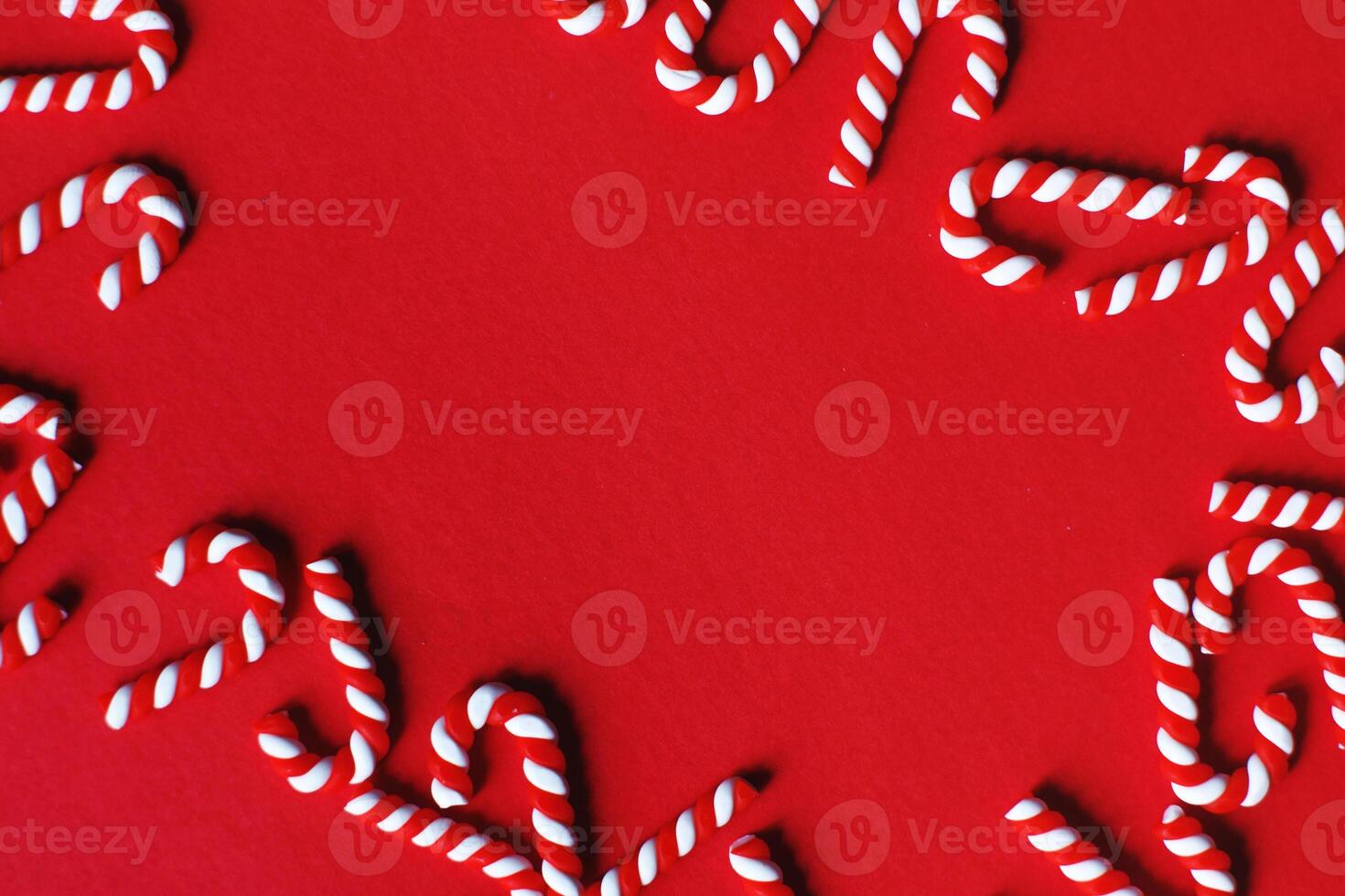 Flat lay Christmas composition with frame of candy canes on a red background. photo