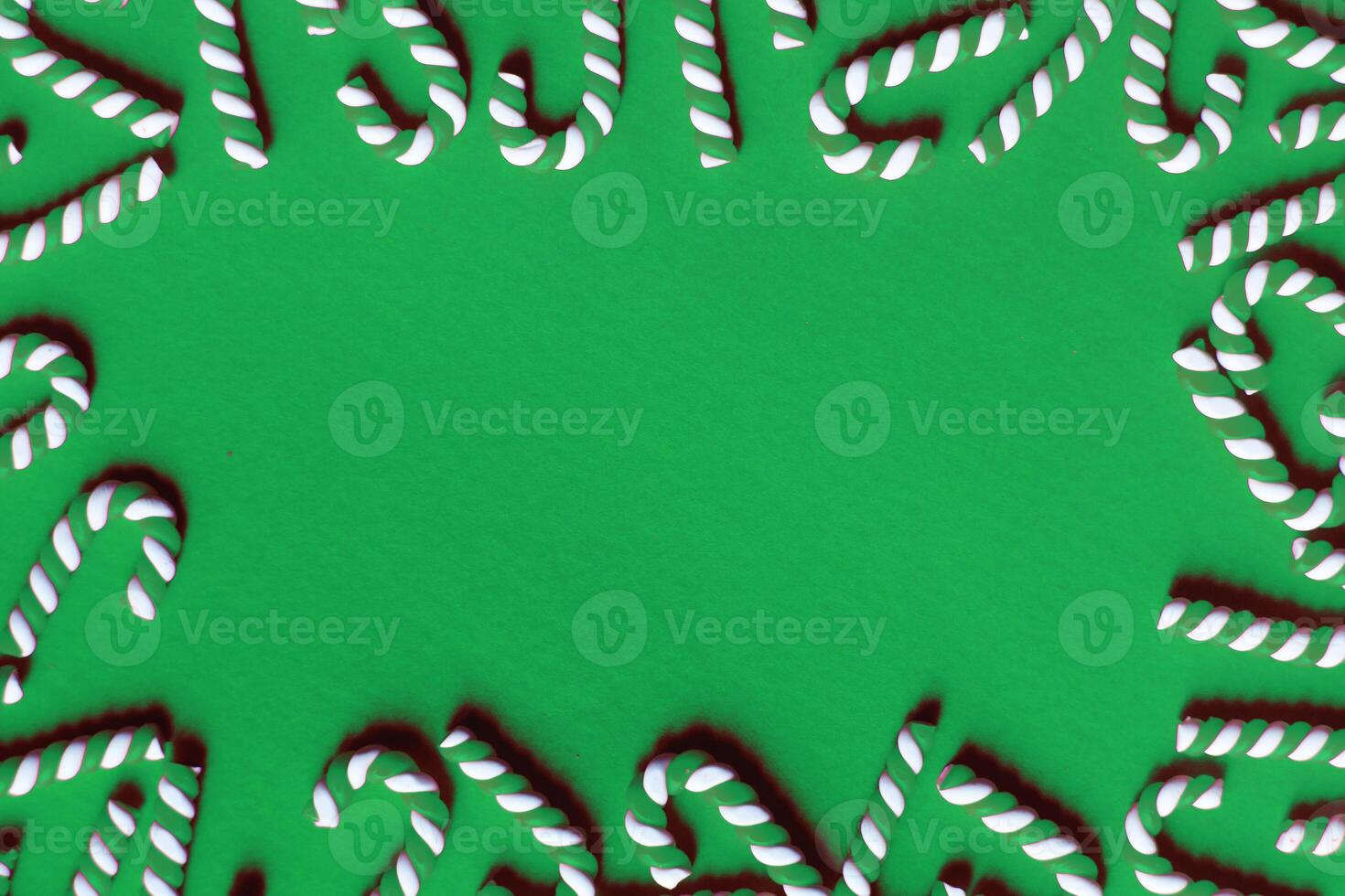 Flat lay Christmas composition with frame of candy canes on a green background. photo