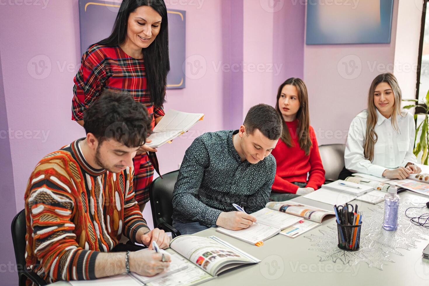 Female teacher explaining subject to her teenage students at language school photo