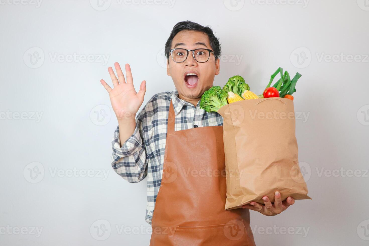 Asian Man with apron shock gesture to grocery shopping bag with finger up with great new idea isolated on plain white photo