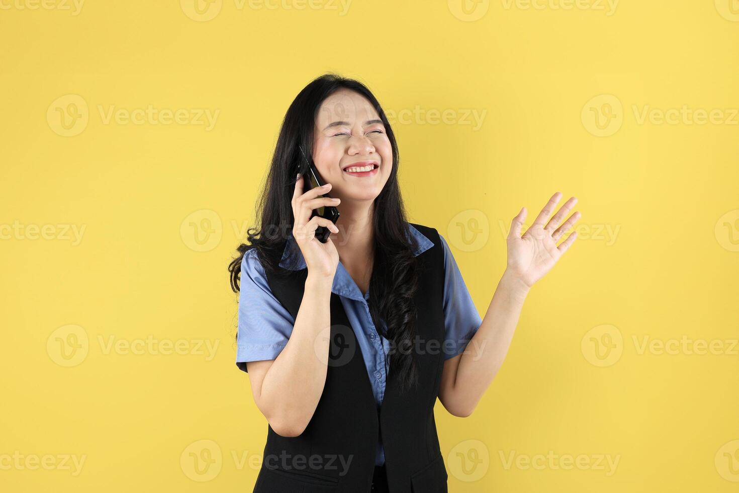 Young Asian Woman Making a Call Using a Cell Phone With Eye Closed, Happy Smiling Gesture. photo