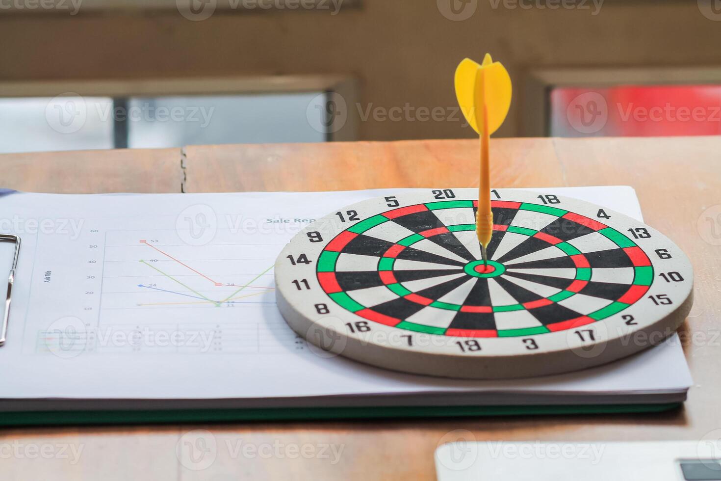 concept of setting business goals or aiming at clear business goals using dartboard and darts as representatives for aiming at precise goals. darts that stuck at center of target are placed on table. photo