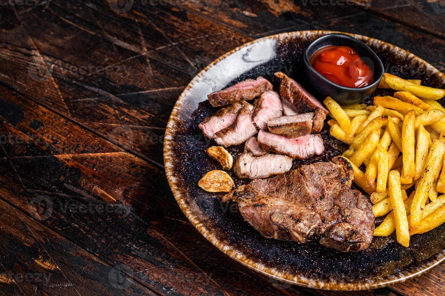Roast BBQ pork chop steak on plate with potato chips. Wooden background. Top view. Copy space photo