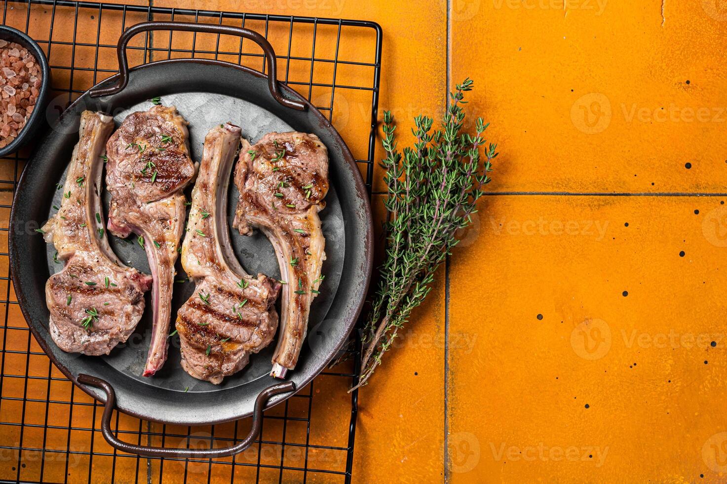 BBQ with Grilled lamb meat chops, mutton steaks with herbs. Orange background. Top view. Copy space photo