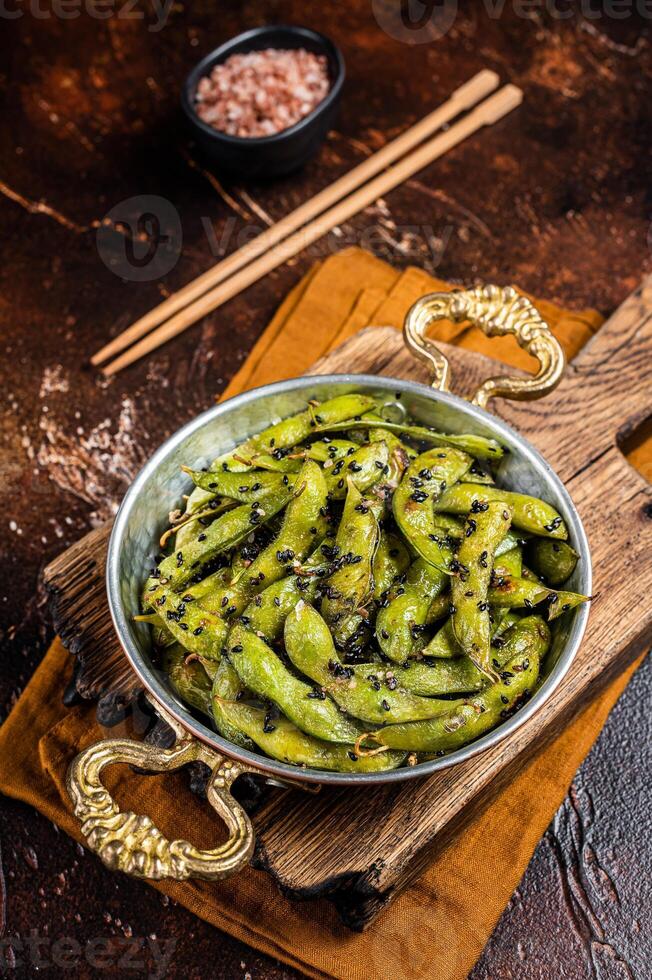 Roasted green Edamame Soy Beans with sea salt and sesame seeds in a skillet. Dark background. Top view photo