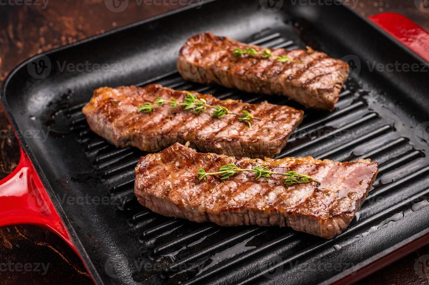 Grilled Tri tip steaks, marbled beef meat on pan with herbs. brown background. top view photo