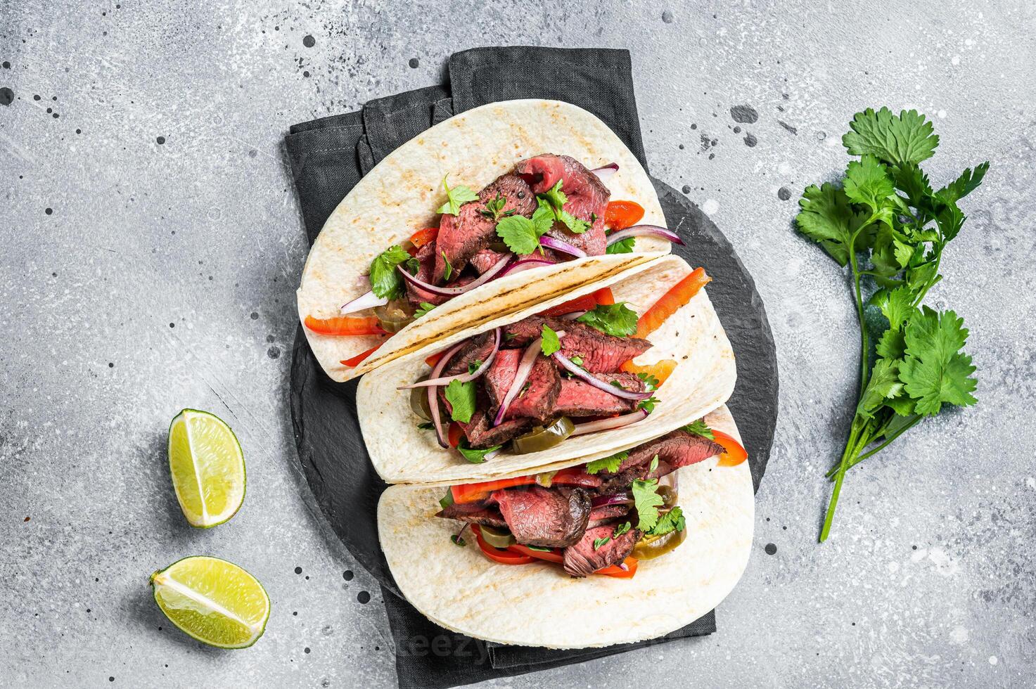 Homemade Mexican Steak Steet Tacos with Cilantro, green sauce, jalapenos and onion. Gray background. top view photo