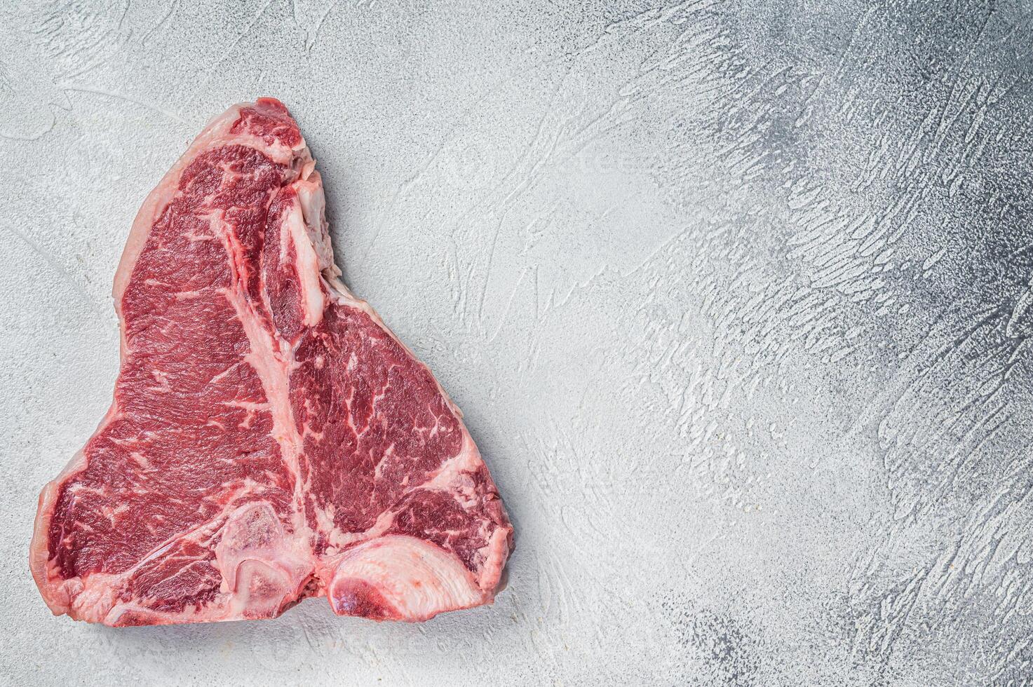 Porterhouse T-bone raw beef meat Steak. White background. Top view. Copy space photo