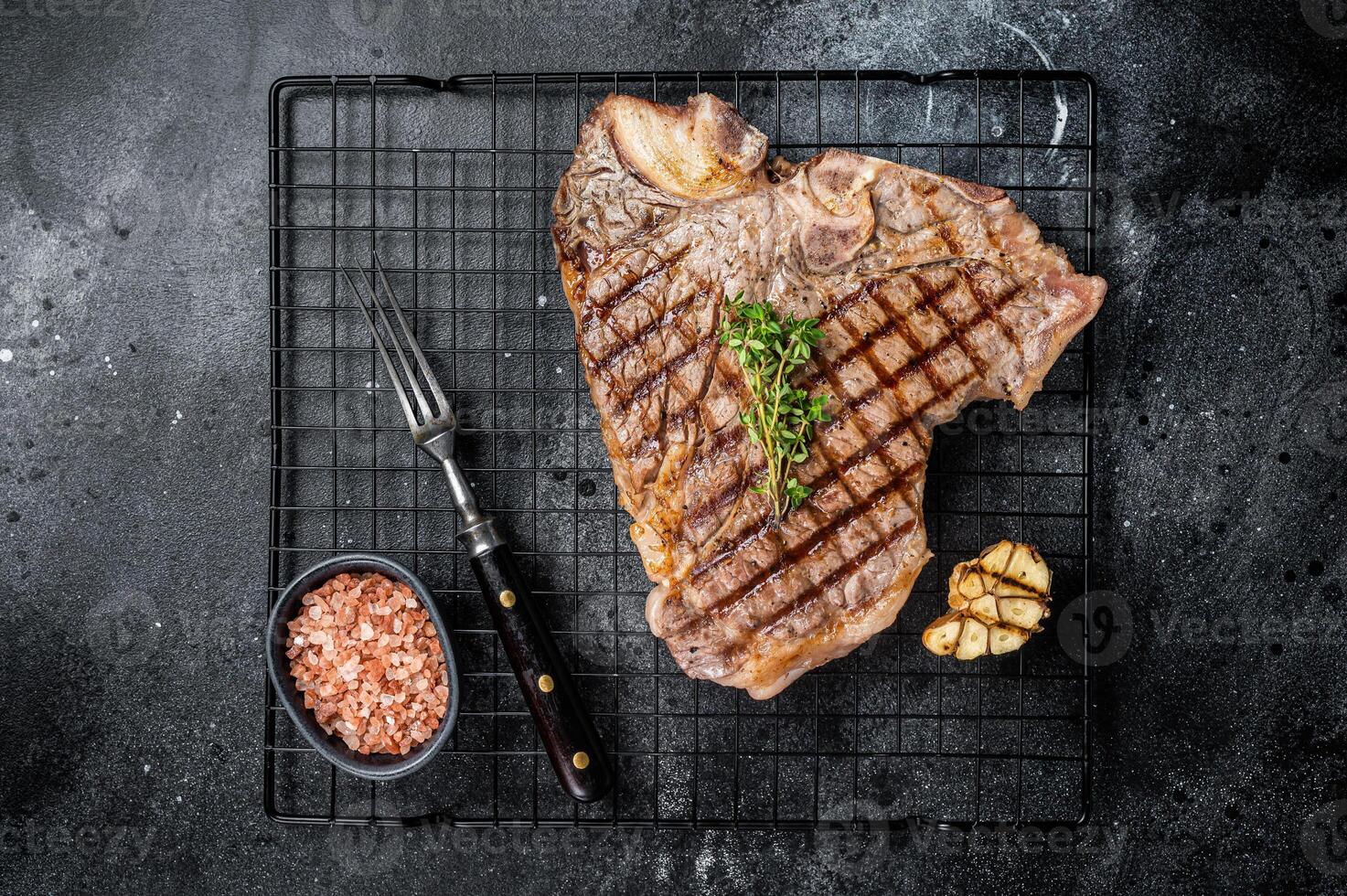 Grilled T-bone or Porterhouse beef meat Steak on a rack. Black background. Top view photo