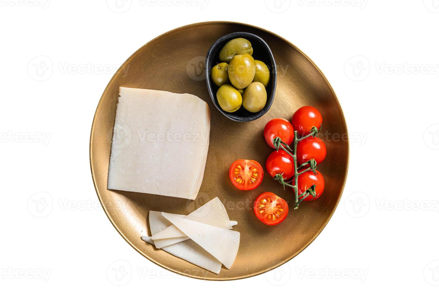 Piece of hard goat cheese in a plate with olives and tomato. Isolated on white background. photo