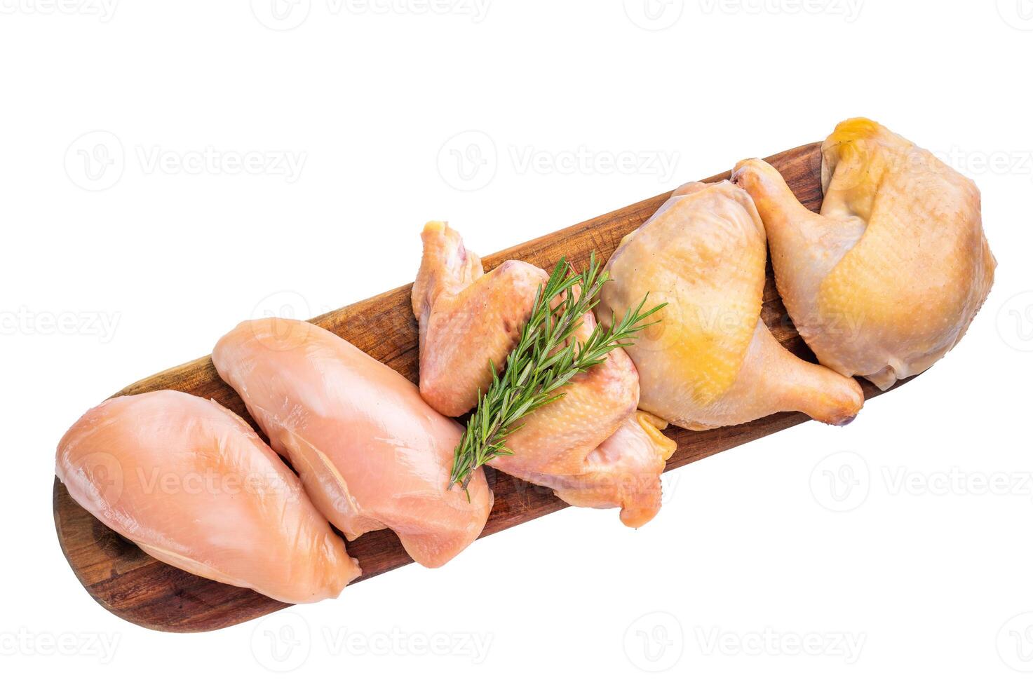 Raw chicken breasts and legs on a wooden cutting board with rosemary, isolated on white background photo