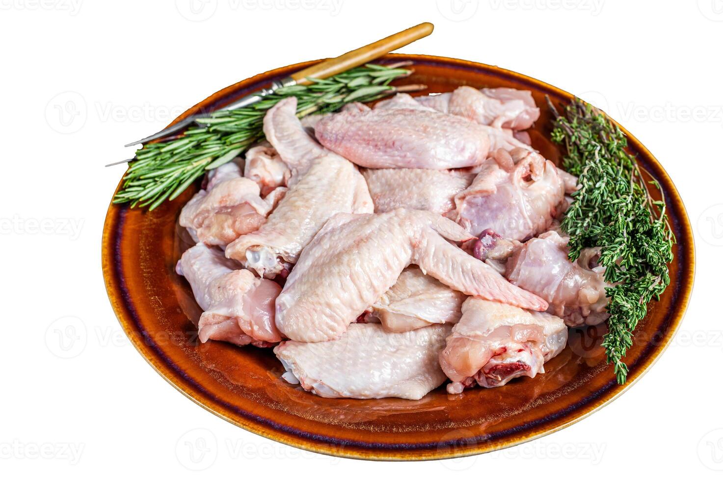 Cut Raw chicken wings in a rustic plate with thyme and rosemary. Isolated on white background. photo
