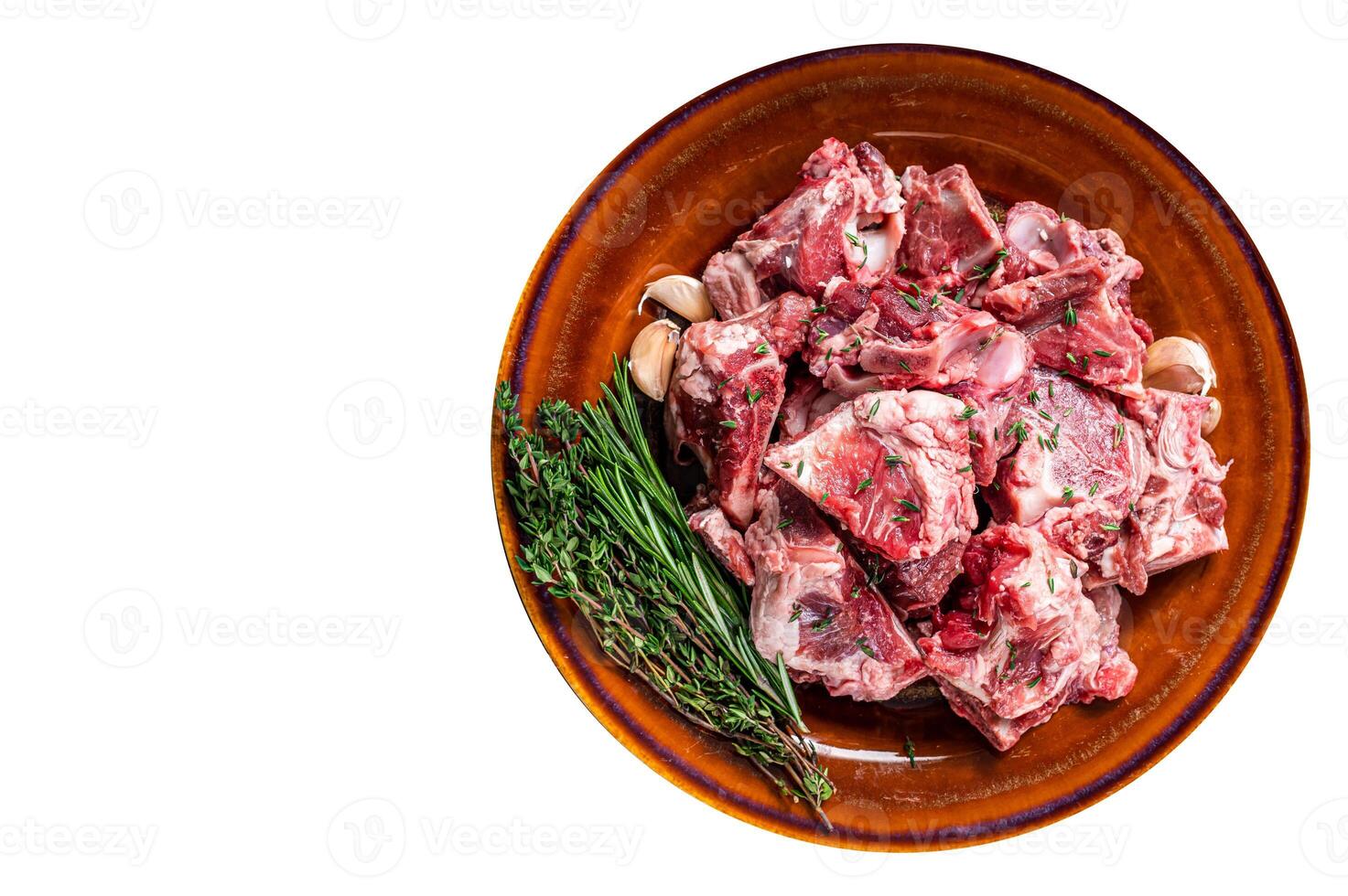 Raw mutton meat diced for goulash or stew with bone on a rustic plate. High quality Isolate, white background. photo