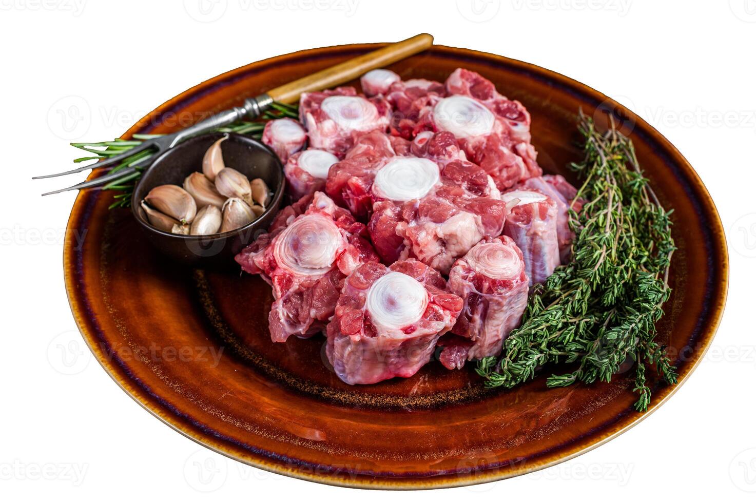Fresh uncooked beef Oxtail cut Meat on rustic plate with herbs. Isolated on white background. photo