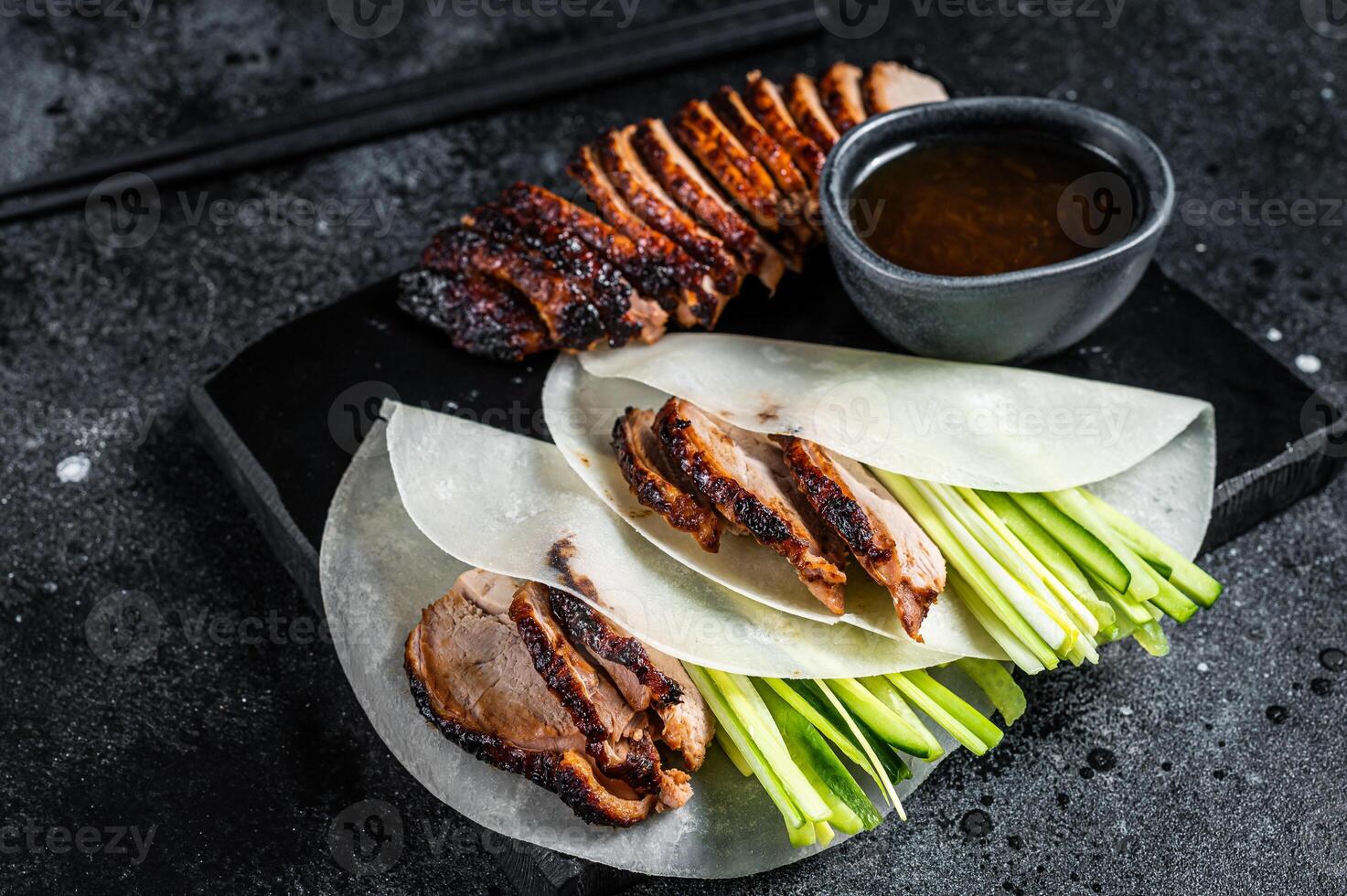 Traditional served Peking Duck with cucumber, green onion, in wheaten chinese pancakes. Black background. Top view photo