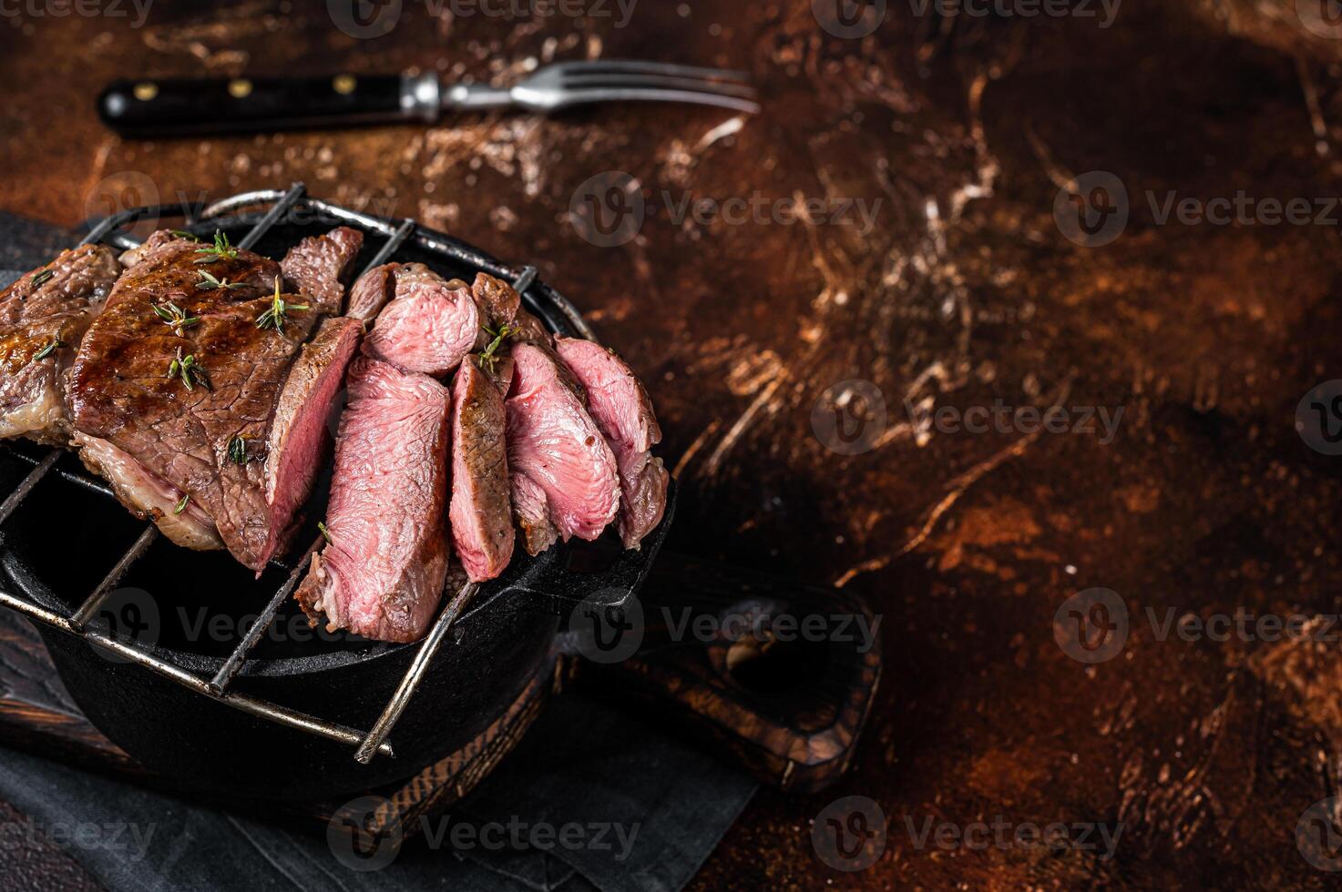 BBQ grilled Mutton fillet chop steaks, sliced lamb meat. Dark background. Top view. Copy space photo