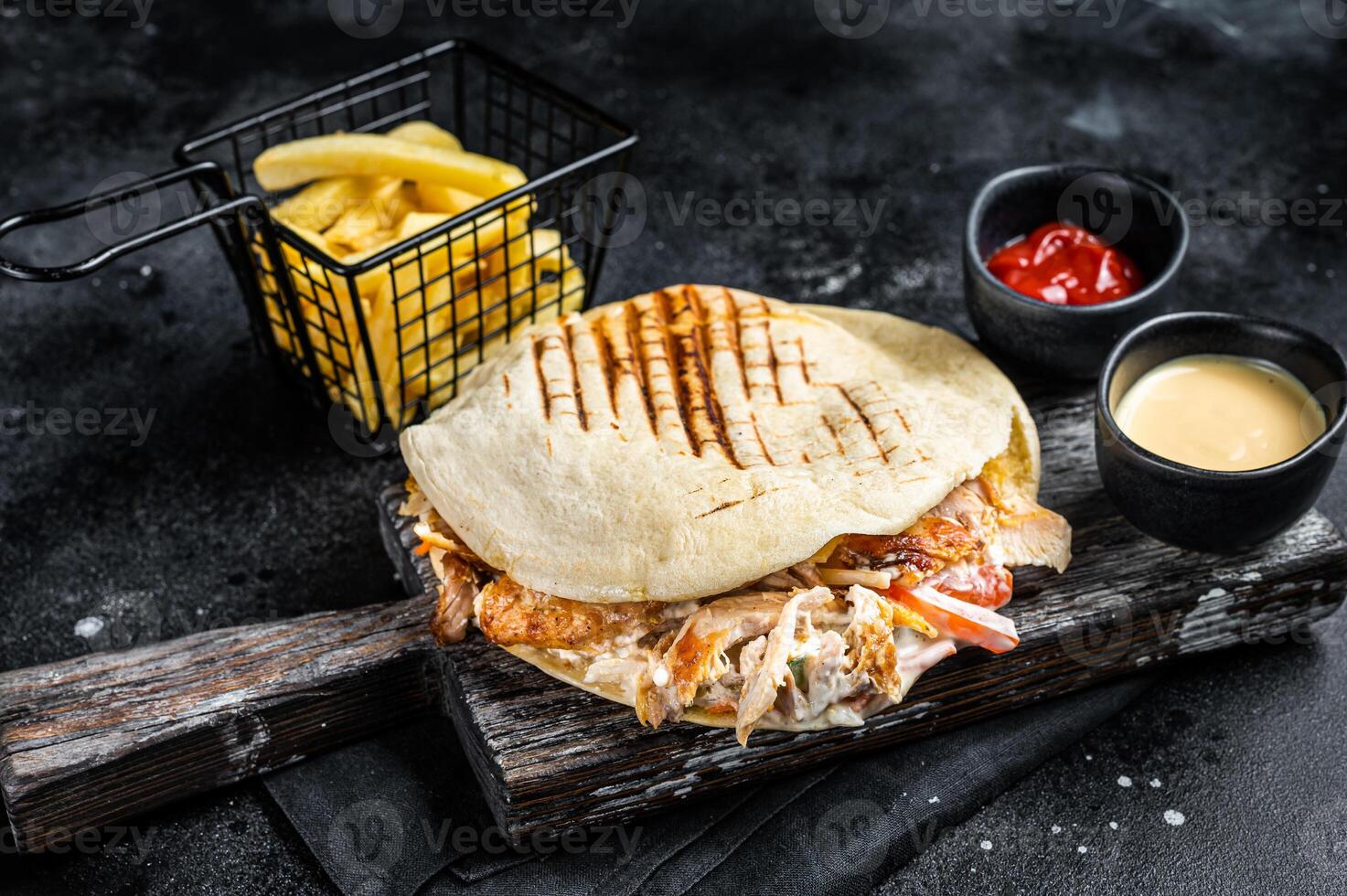 Turkish doner kebab in grilled pita bread with chicken meat. Black background. Top view photo