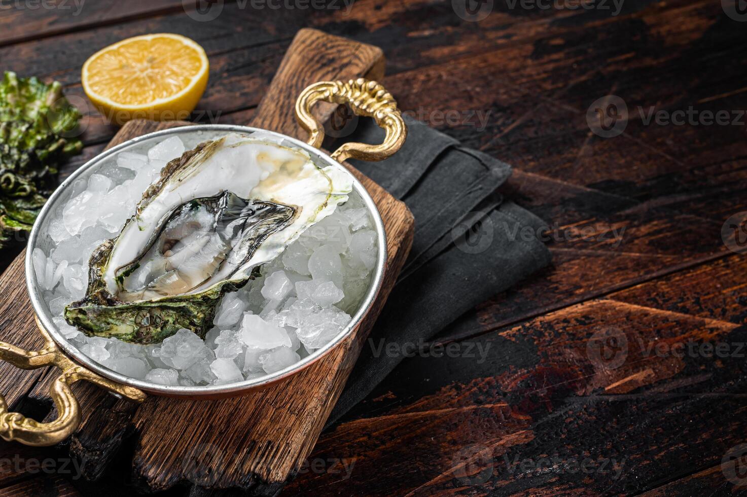 Appetizing raw oyster with ice cubes in a skillet . Wooden background. Top view. Copy space photo