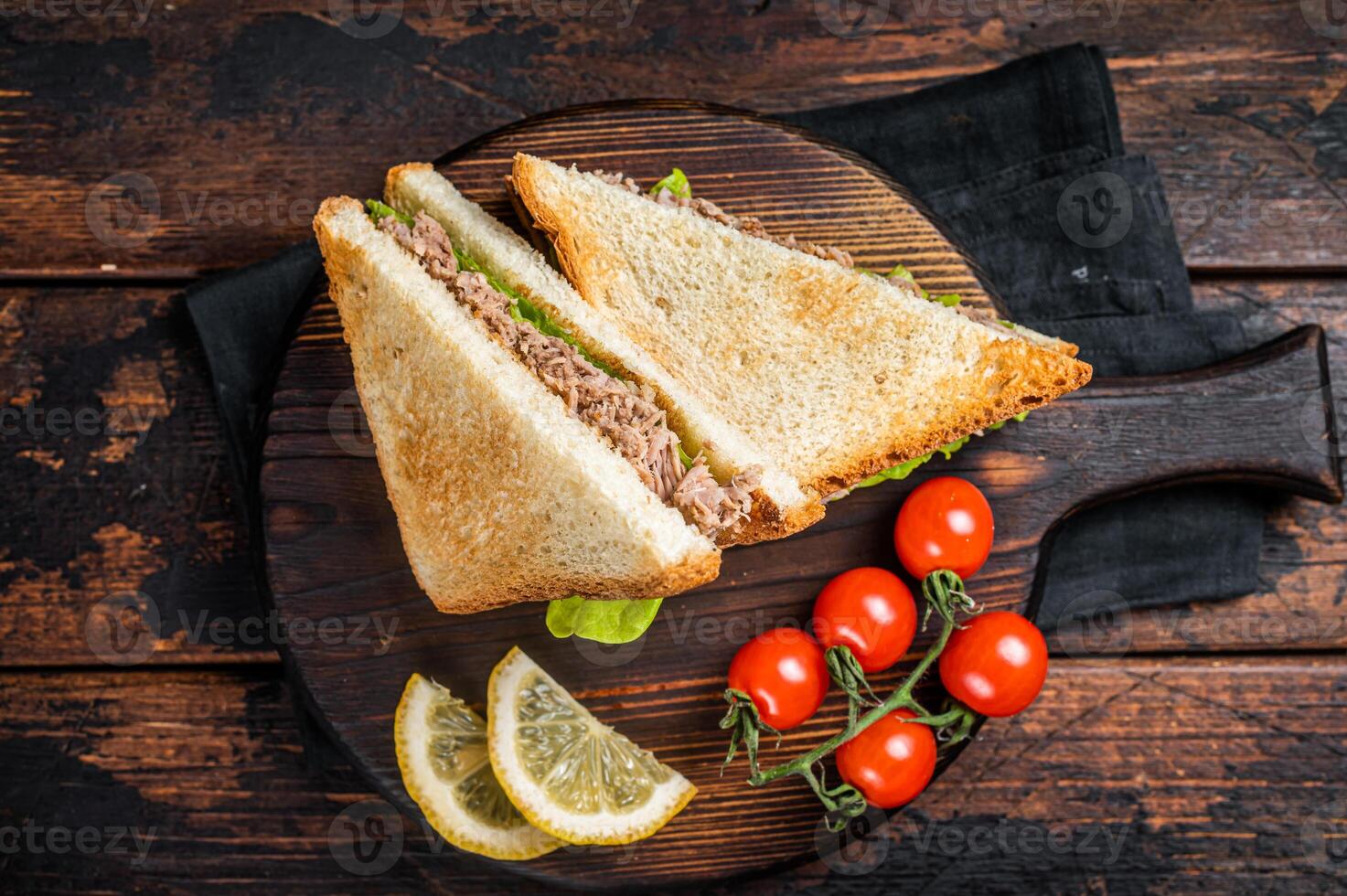 Healthy Tuna Sandwich with Lettuce on wooden board. Dark background. Top view photo