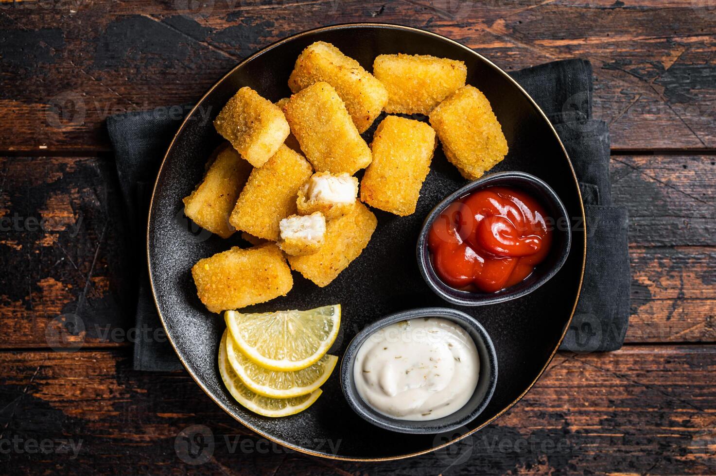 Fried Fish Sticks Fingers with sauce in a plate. Wooden background. Top view photo