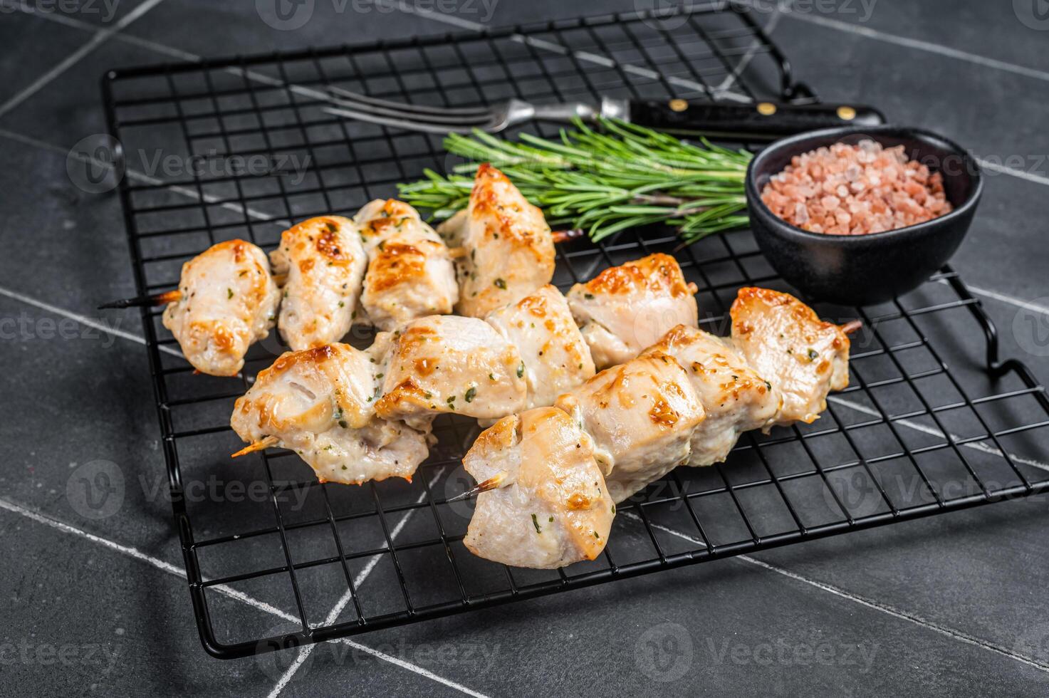 Chicken shish kebab, grilled skewers with herbs and spices on a rack. Black background. Top view photo