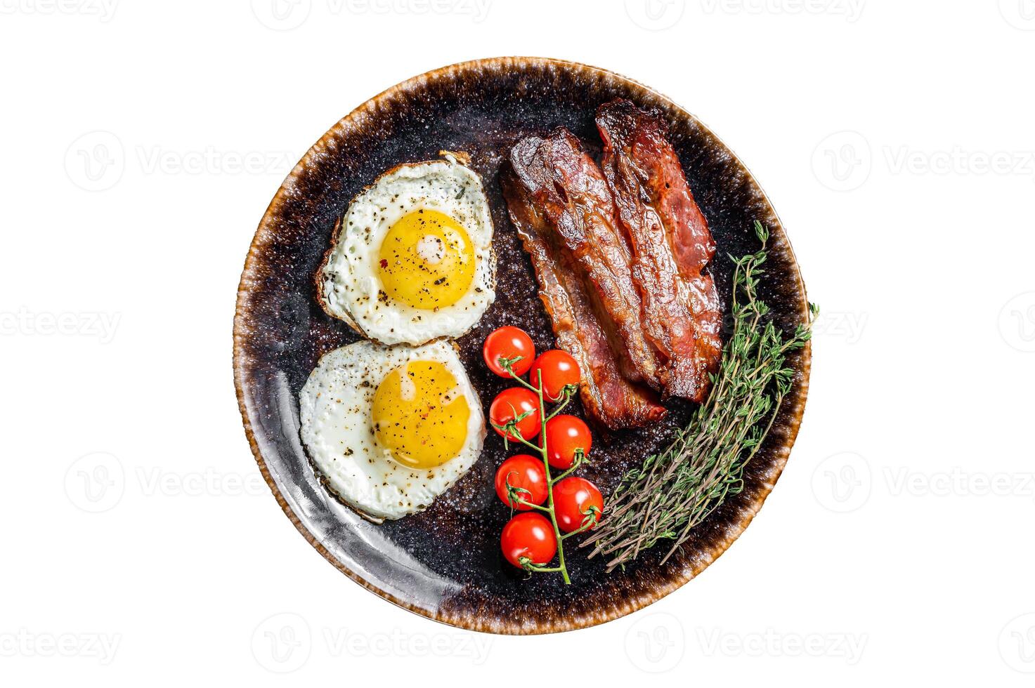 Breakfast with fried eggs and bacon with herbs in plate. Isolated on white background. photo