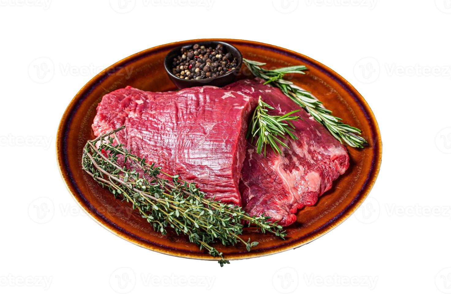 Two Flap or Flank raw beef steaks on a rustic plate with herbs. Isolated on white background. photo