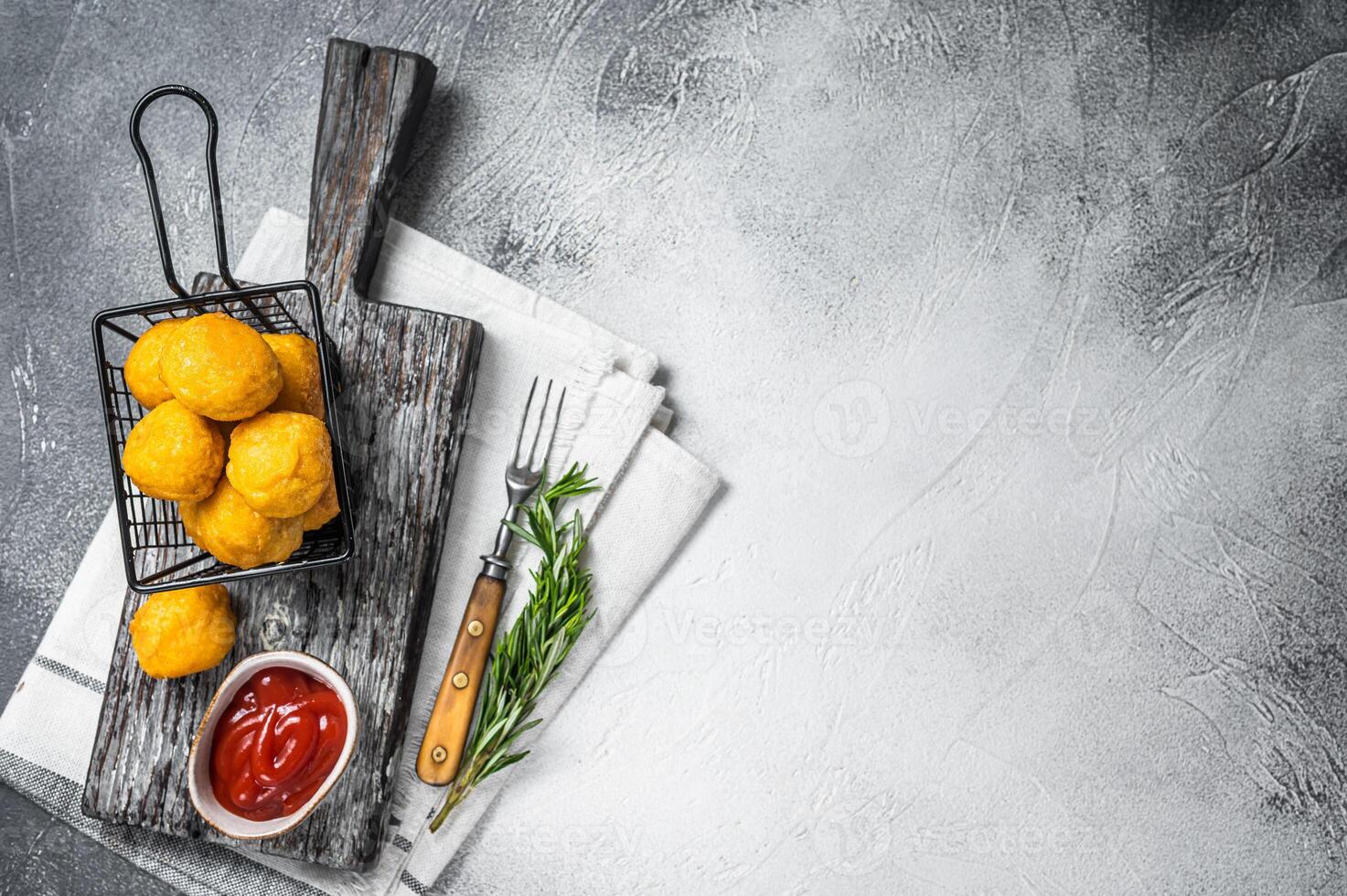 Fried potato cheese balls croquettes with tomato ketchup served in a basket. White background. Top view. Copy space photo