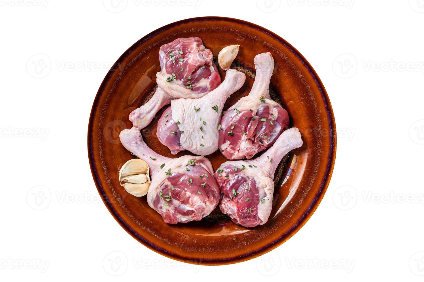 Raw Poultry meat - Duck legs drumsticks on a rustic plate with herbs. Isolated, white background. Top view. photo