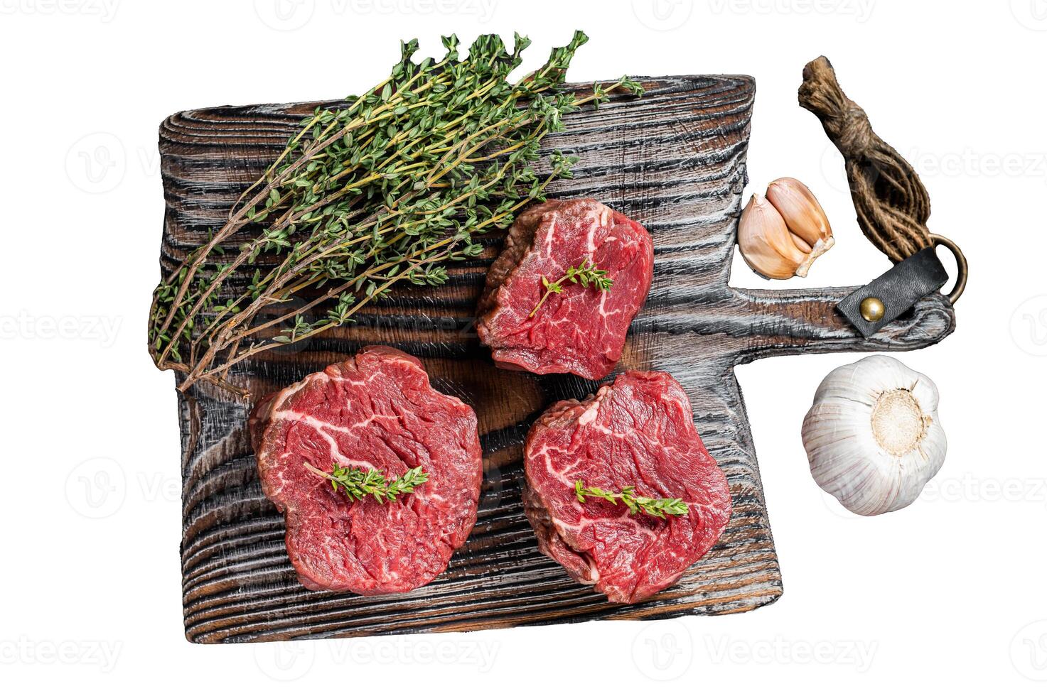 Prime raw Fillet mignon steaks on a wooden board with thyme and garlic Isolated on white background, top view. photo