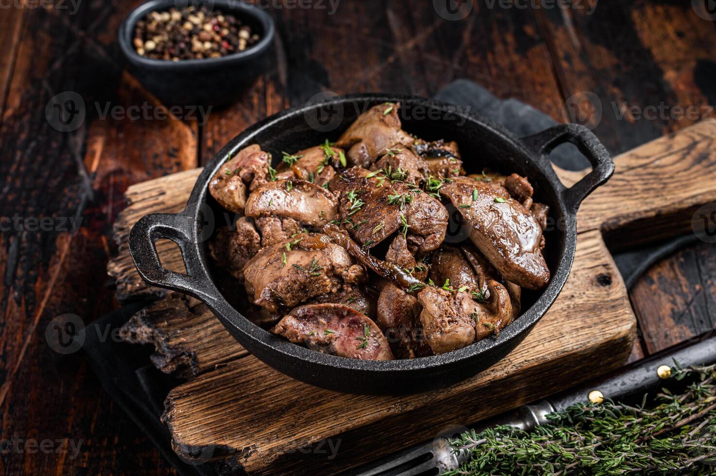 Roasted chicken liver with onions in a skillet. Wooden background. Top view photo
