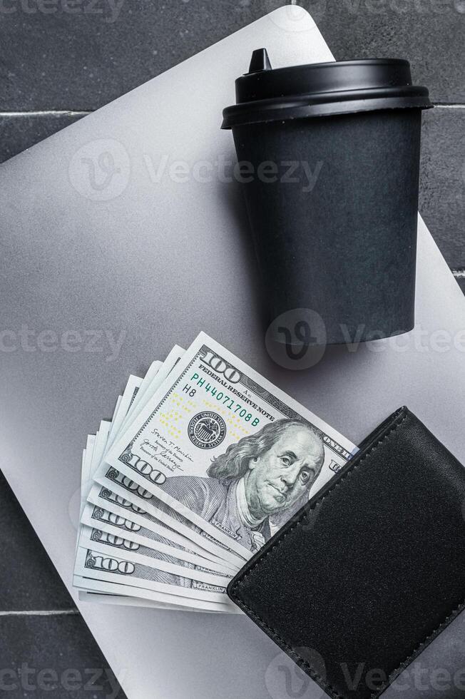 Top view of laptop, wallet with dollars and cup of espresso coffee. Black background. Top view. Copy space photo
