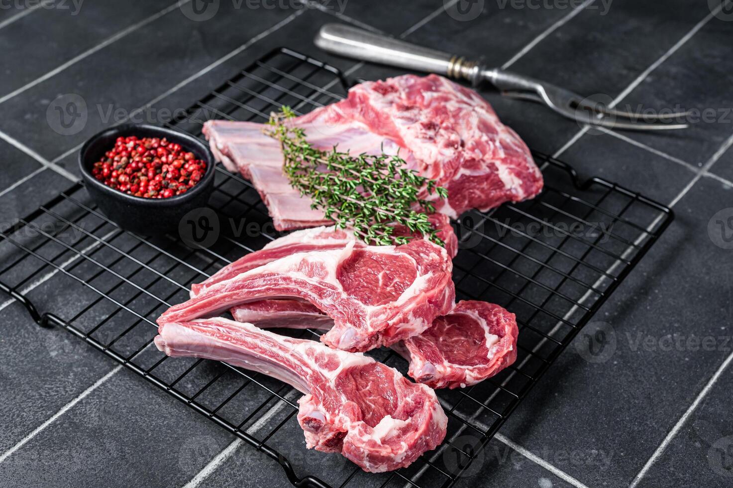 Fresh Raw lamb meat chop steaks on kitchen table with spices and herbs. Black background. Top view photo