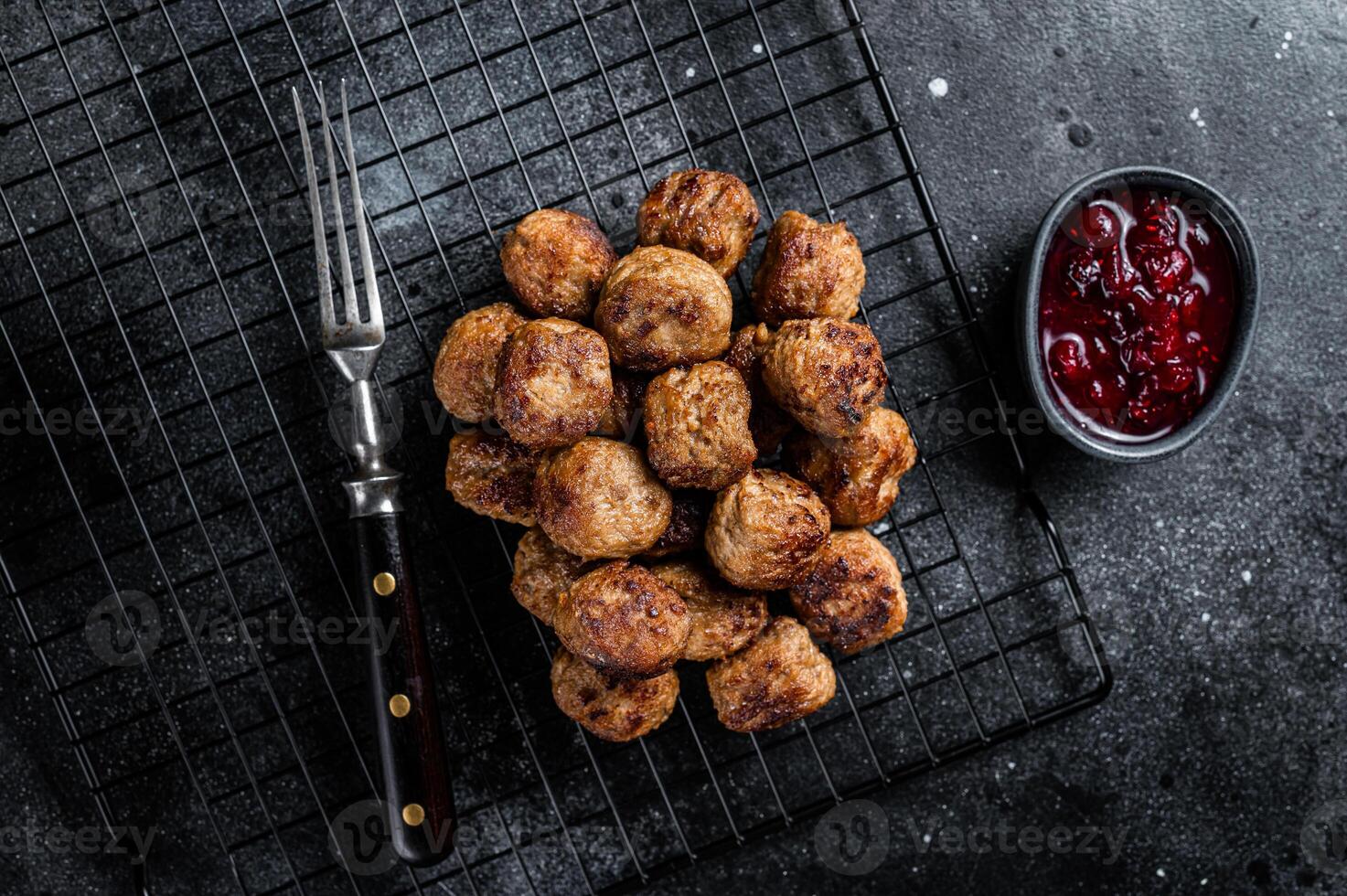 Swedish meatballs with lingonberries and gravy sauce. Black background. Top view photo