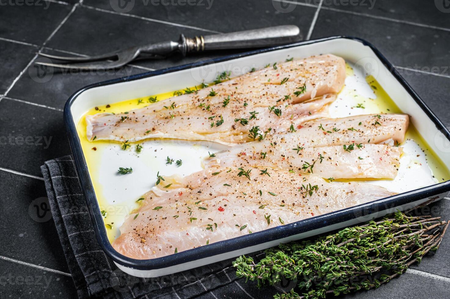 Marinated ocean red perch fillet with olive oil, thyme and spices. Black background. Top view photo