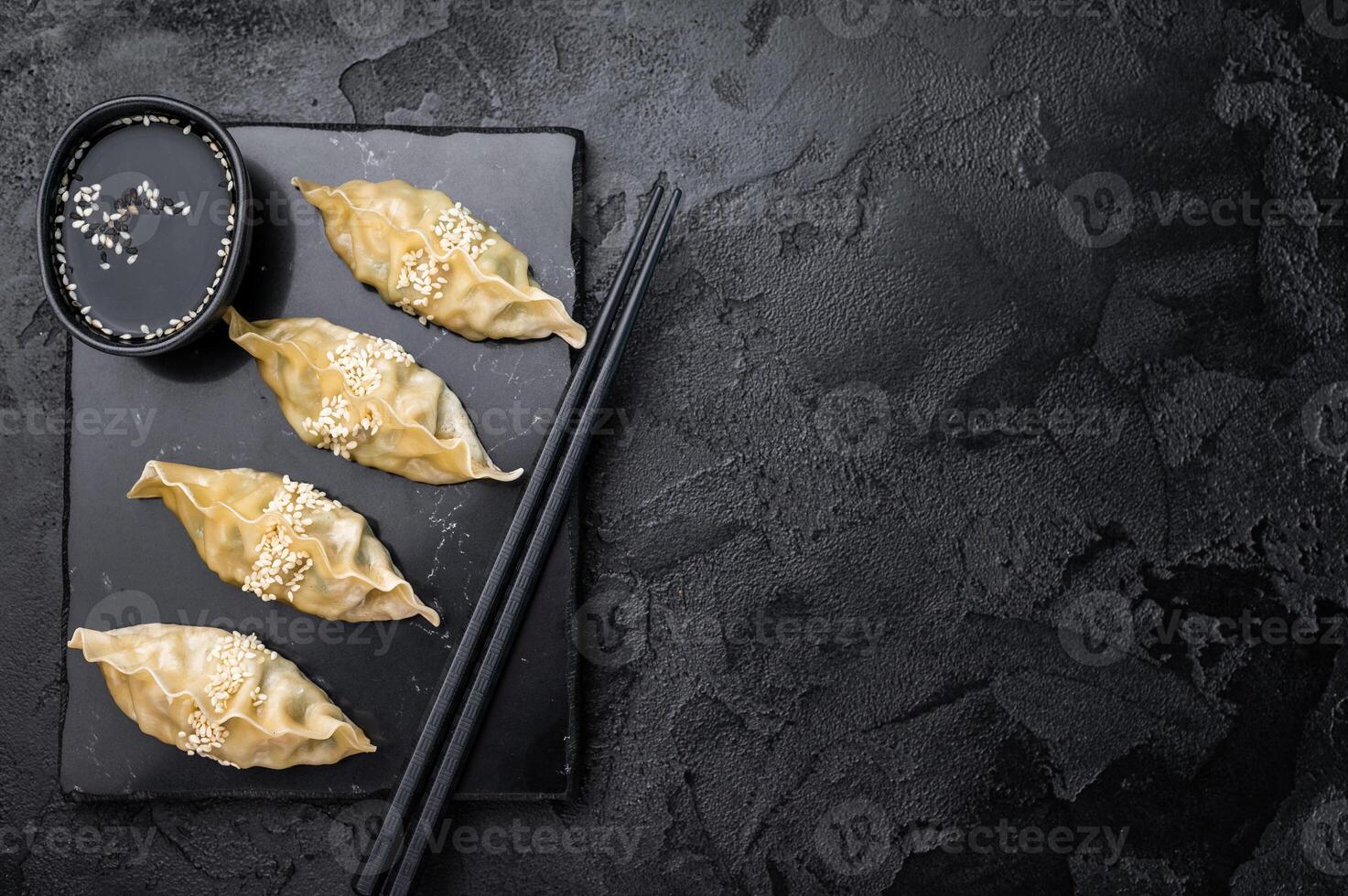 Steamed Chinese Jiaozi Dumplings with meat and vegetables on marble board. black background. top view photo